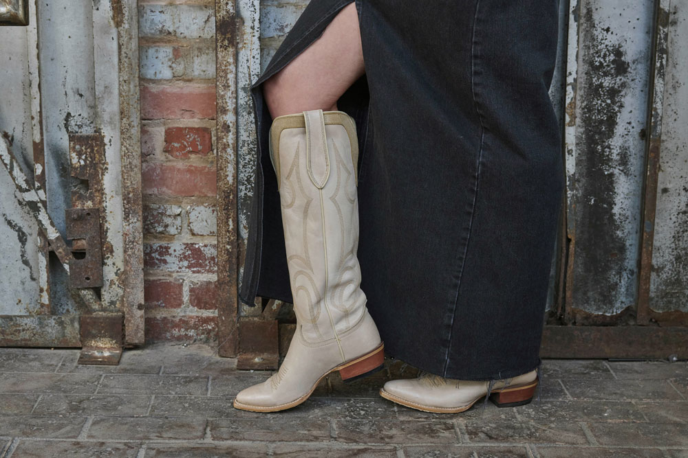 Woman wearing Verlie 17” Western boots in cream with a long skirt. 